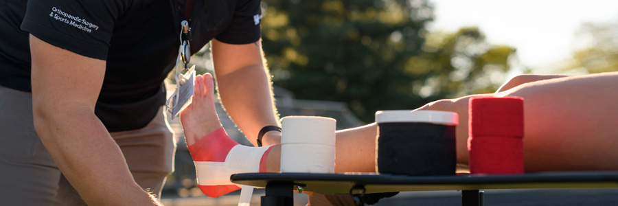 教练科迪·贝格利(Cody Begley)正在包裹一名足球运动员的腿。
