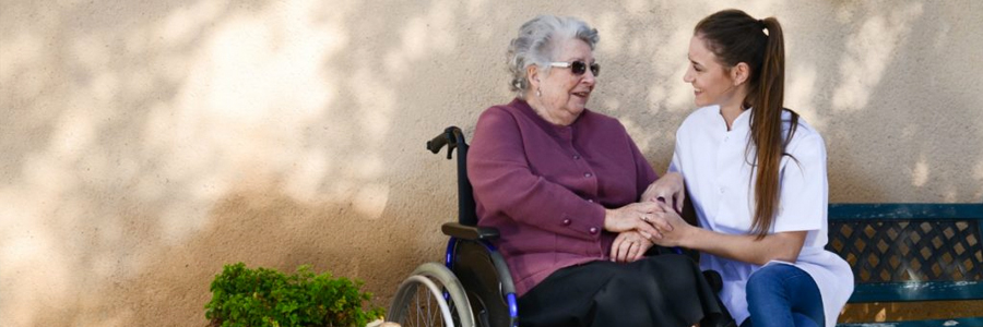 一个照顾者与一位上了年纪的女病人坐在轮椅上。