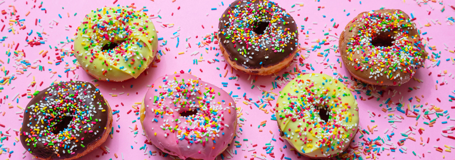 粉红色背景上的一排彩色甜甜圈。