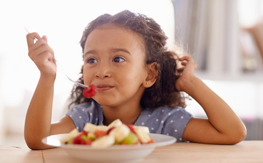 一个小女孩吃着一碗水果。