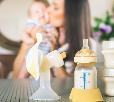 一个母乳泵和奶瓶与母亲和婴儿的背景。