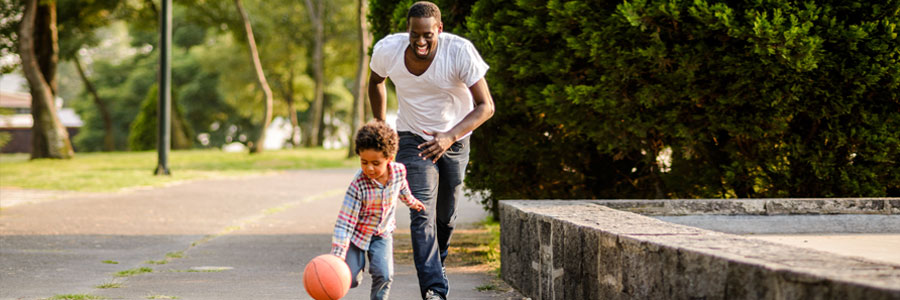 一个父亲和他的小儿子和篮球打球。