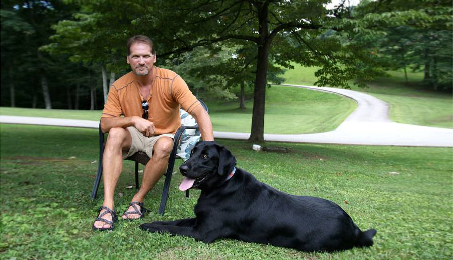 Myrl Sizemore坐在户外，他的狗Sarge在他的脚边。