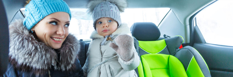 母亲和婴儿的女儿穿着冬天的衣服在一辆汽车。