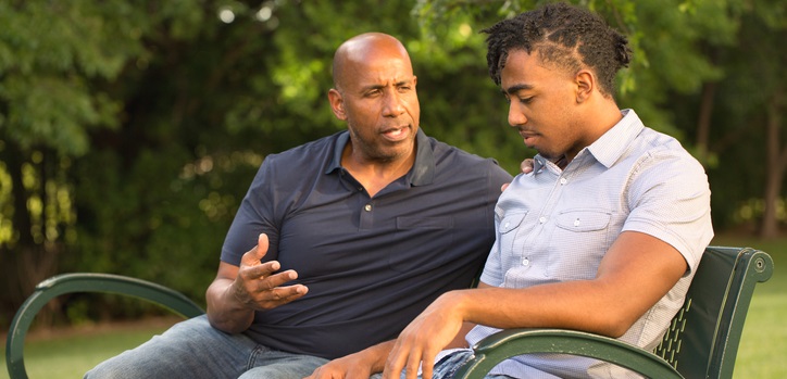 父亲在公园的长凳上和儿子交谈。
