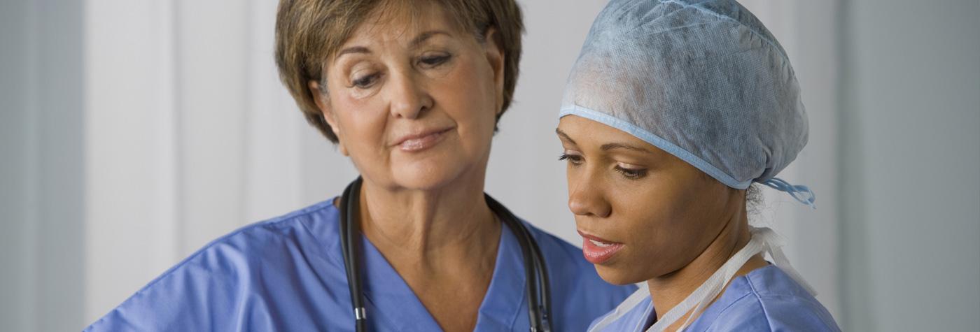 两名女医生在阅读和讨论患者图表时穿着蓝色磨砂膏