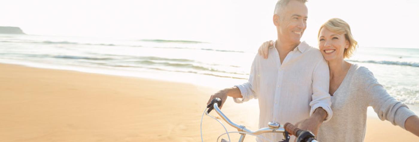 一对中年夫妇骑着自行车在海滩上。