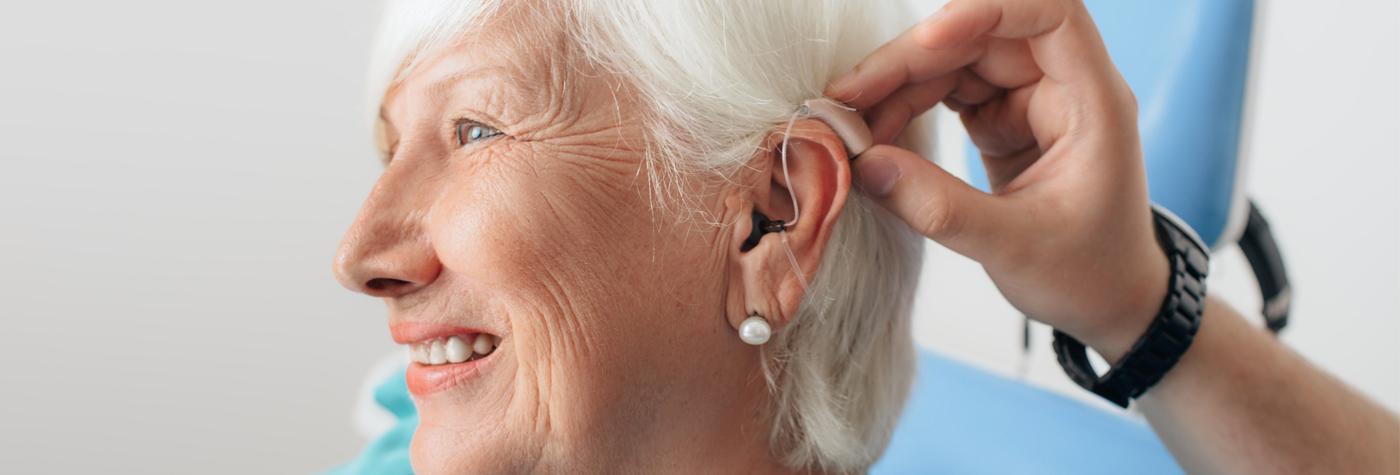 听力学家把助听器放进病人的耳朵里。