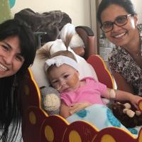 的照片Shenoi博士和Kailey护理团队的一员微笑着他们用婴儿Kailey摆个姿势照相。