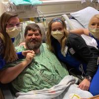 罗纳德和他的团队护士的照片微笑的照片从医院的病床上。