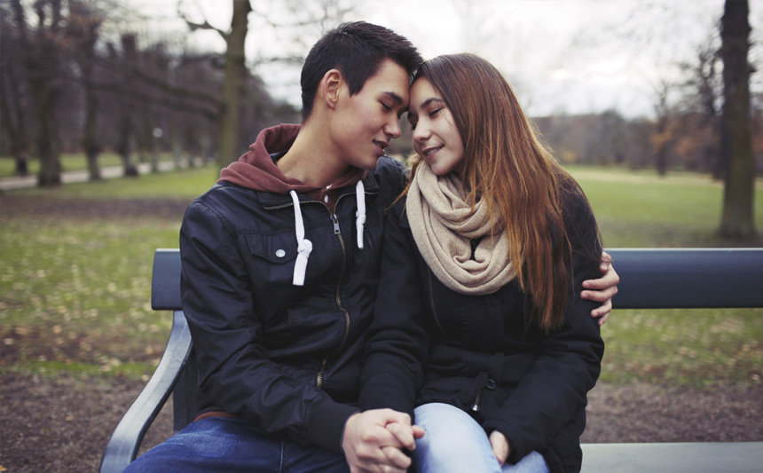 一对十几岁的情侣坐在公园的长椅上。